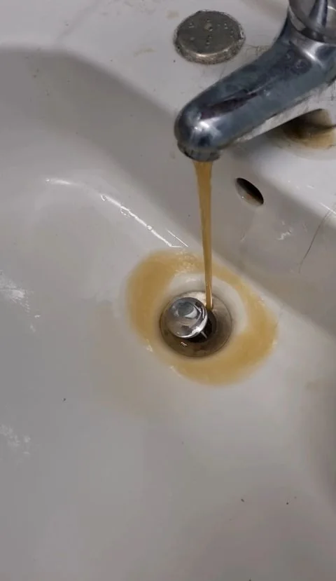 Flussaggio di una tubazione dopo una bonifica: dal rubinetto esce acqua carica di deposito